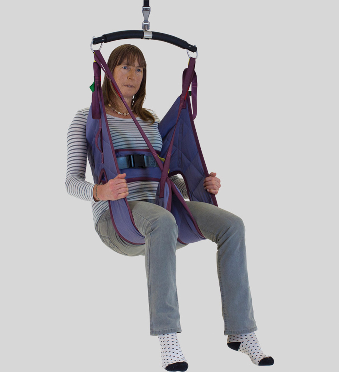 Person seated in a hygienic sling with back and leg support