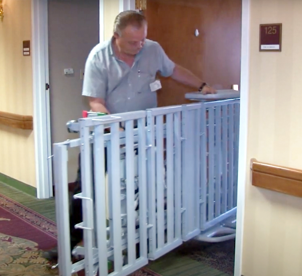 Man pushing folded up medical bed through a doorway